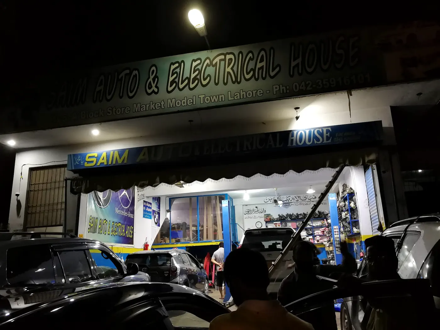 The Saim Autos shop board lit up at night in A Block Store Market